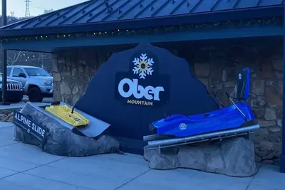 Ober Mountain sign with mountain coaster and alpine slide cart at location on the Parkway